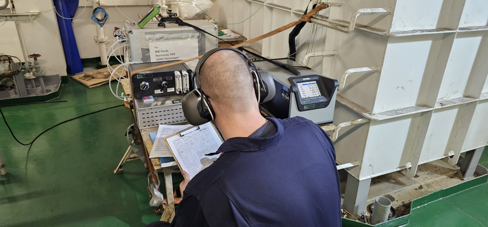 ME-Tech technician reading the measurement sheet in front of the analyzer rack